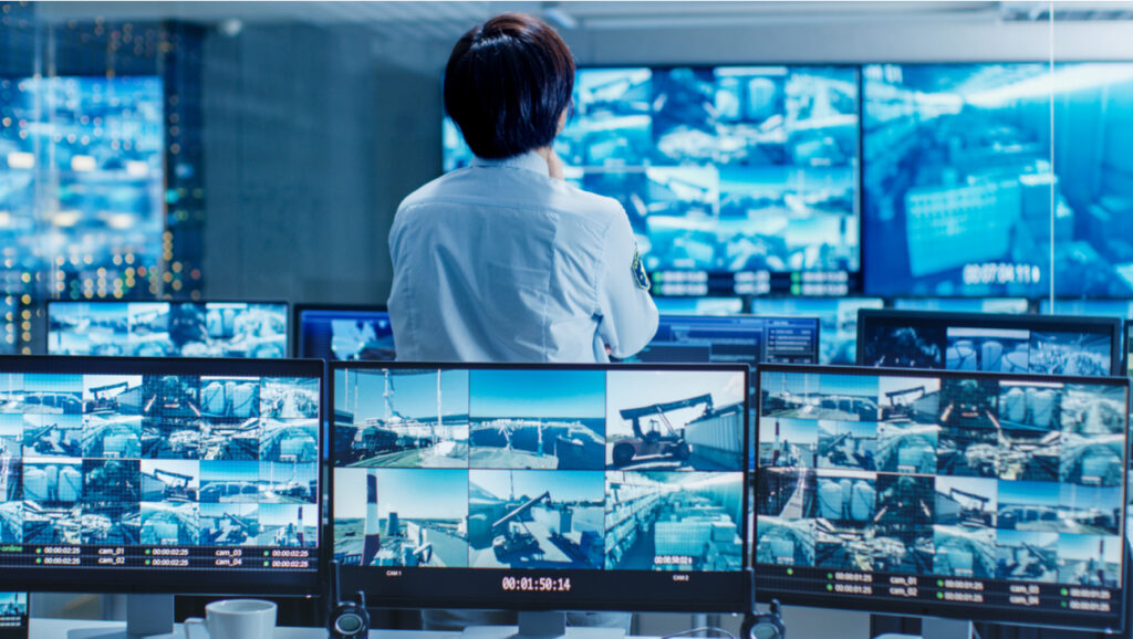 in the security control room officer monitors multiple screens for suspicious activities